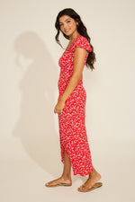 Woman wearing a red floral dress on a beige background