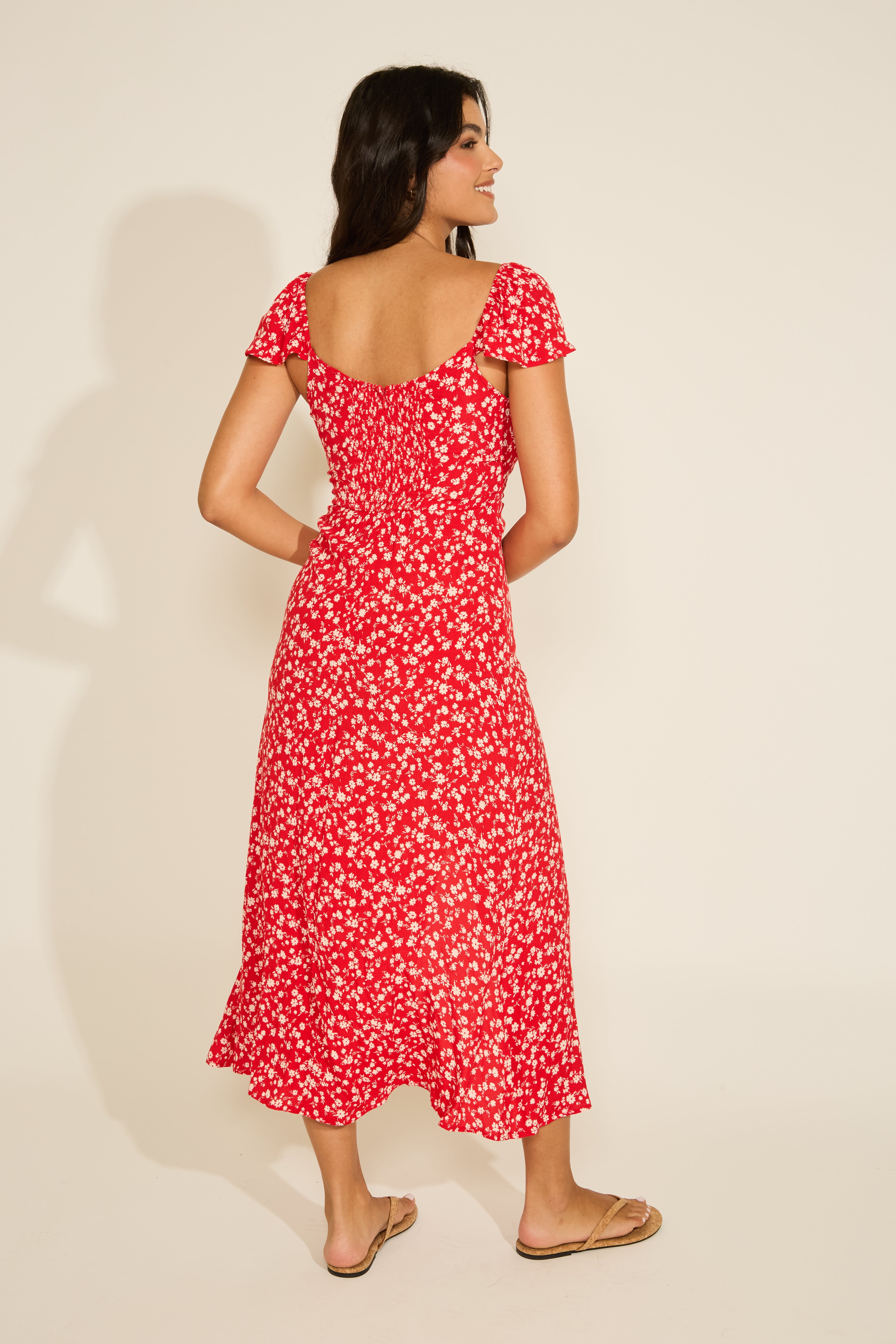 Woman wearing a red floral dress against a plain background