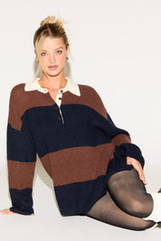 Woman wearing a brown and navy striped sweater sitting on a white surface.