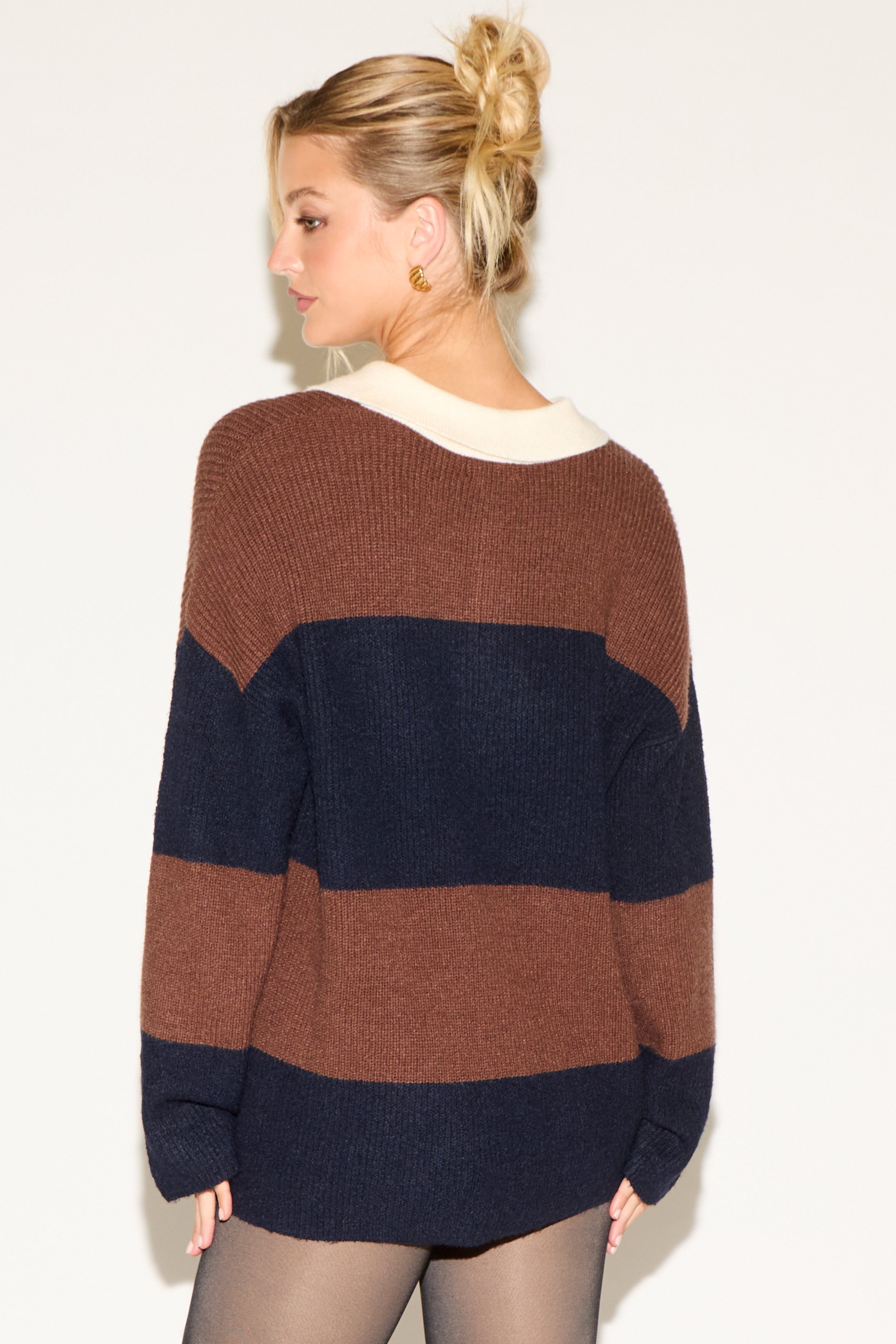 Woman wearing a brown and navy striped sweater against a white background