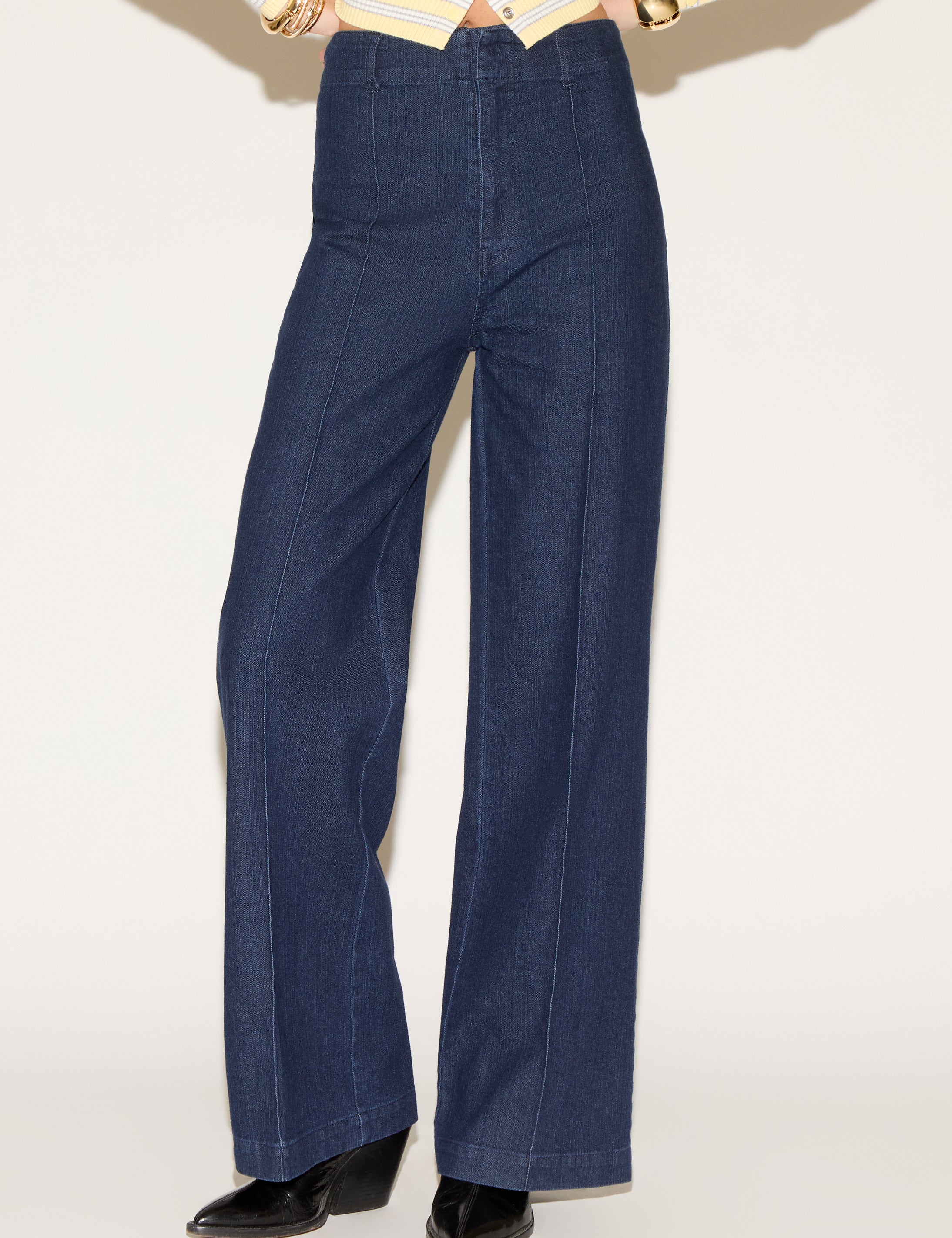 Person wearing dark blue wide-legged jeans and a yellow-striped sweater with long sleeves. Their pose suggests confidence and style.