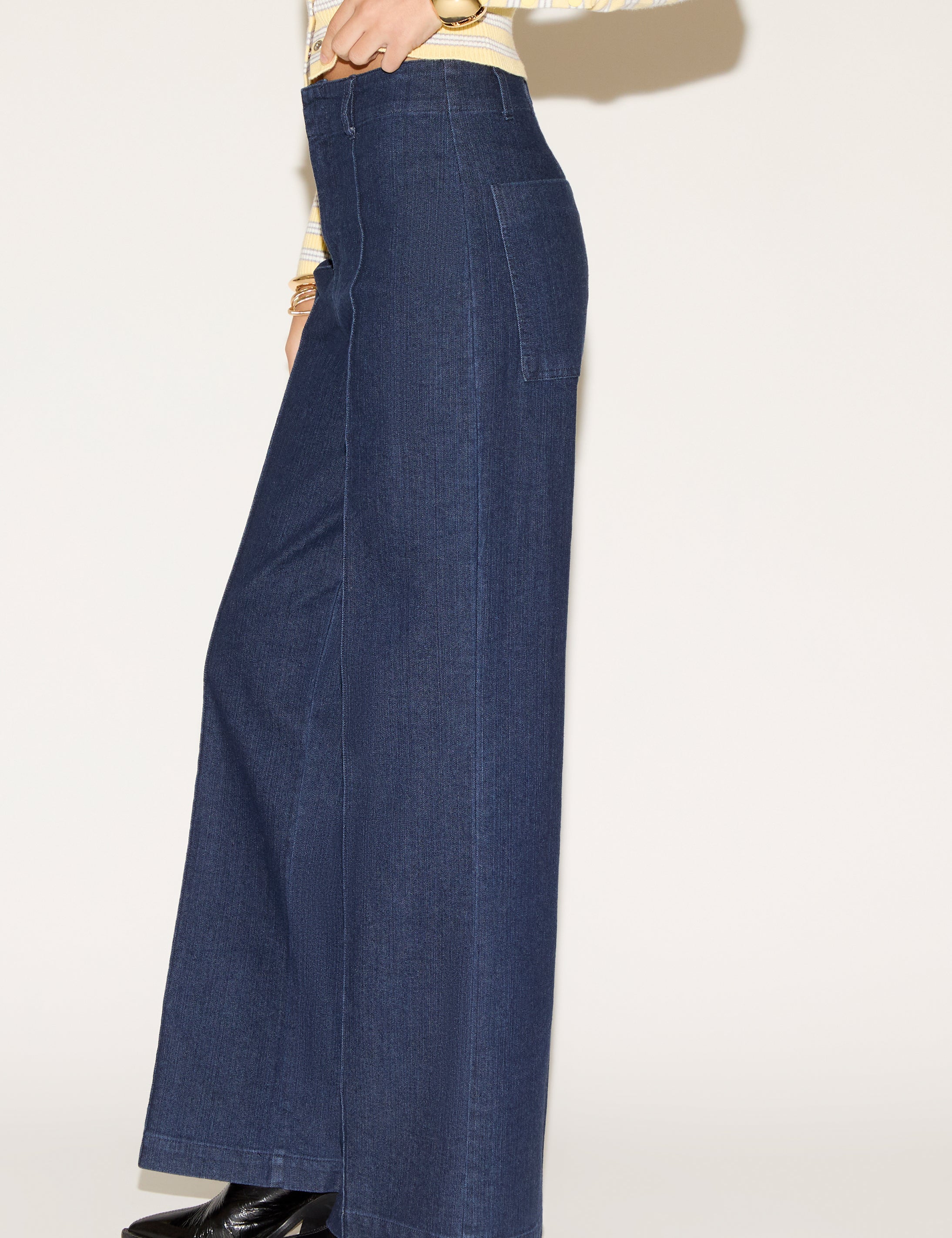 Person wearing dark blue wide-legged jeans and a yellow-striped sweater with long sleeves. Their pose suggests confidence and style.