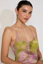 Woman wearing a colorful floral dress against a plain background