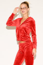 Woman wearing a red velour tracksuit against a white background