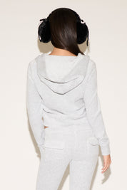 Person wearing a light gray hoodie and pants set on a white background