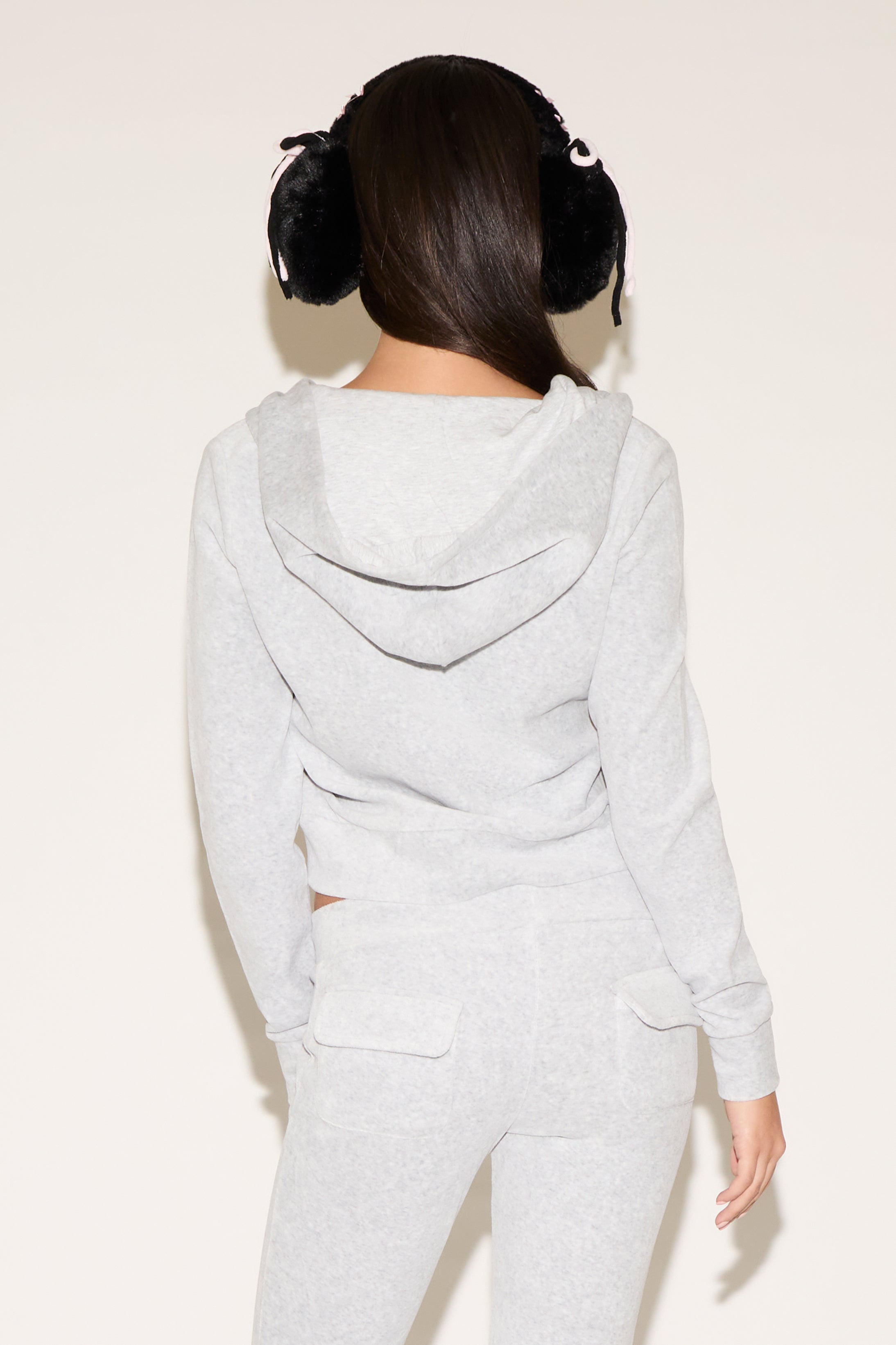 Person wearing a light gray hoodie and pants set on a white background