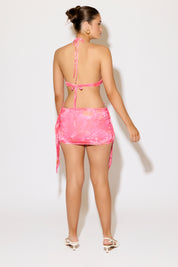 Woman wearing a pink bikini and skirt set on a white background