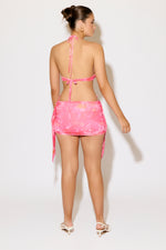 Woman wearing a pink bikini and skirt set on a white background
