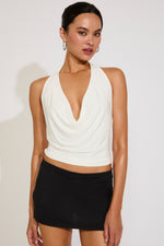 Woman wearing a white halter top and black skirt on a plain background