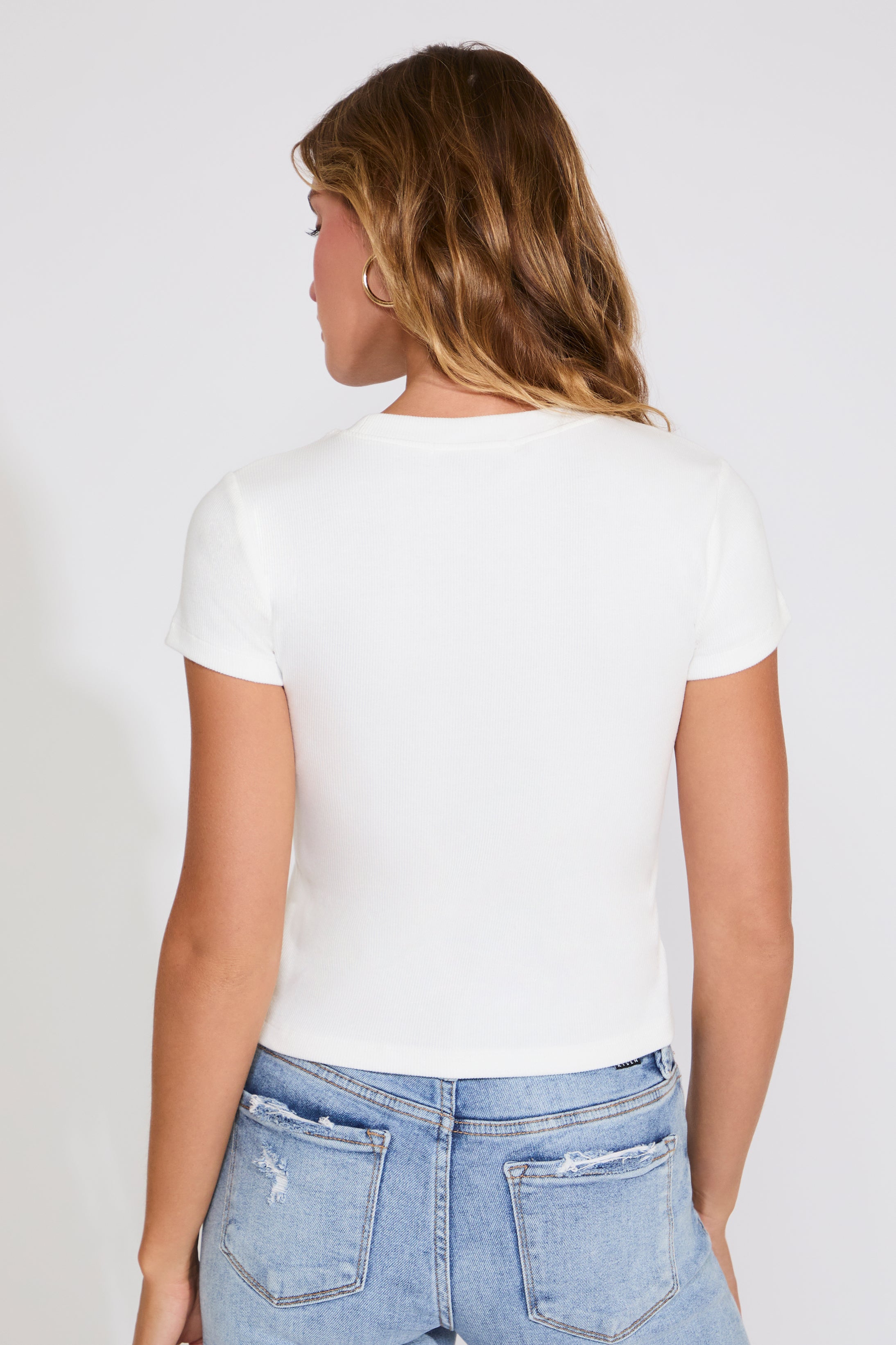 Person wearing a white t-shirt and blue jeans on a plain background
