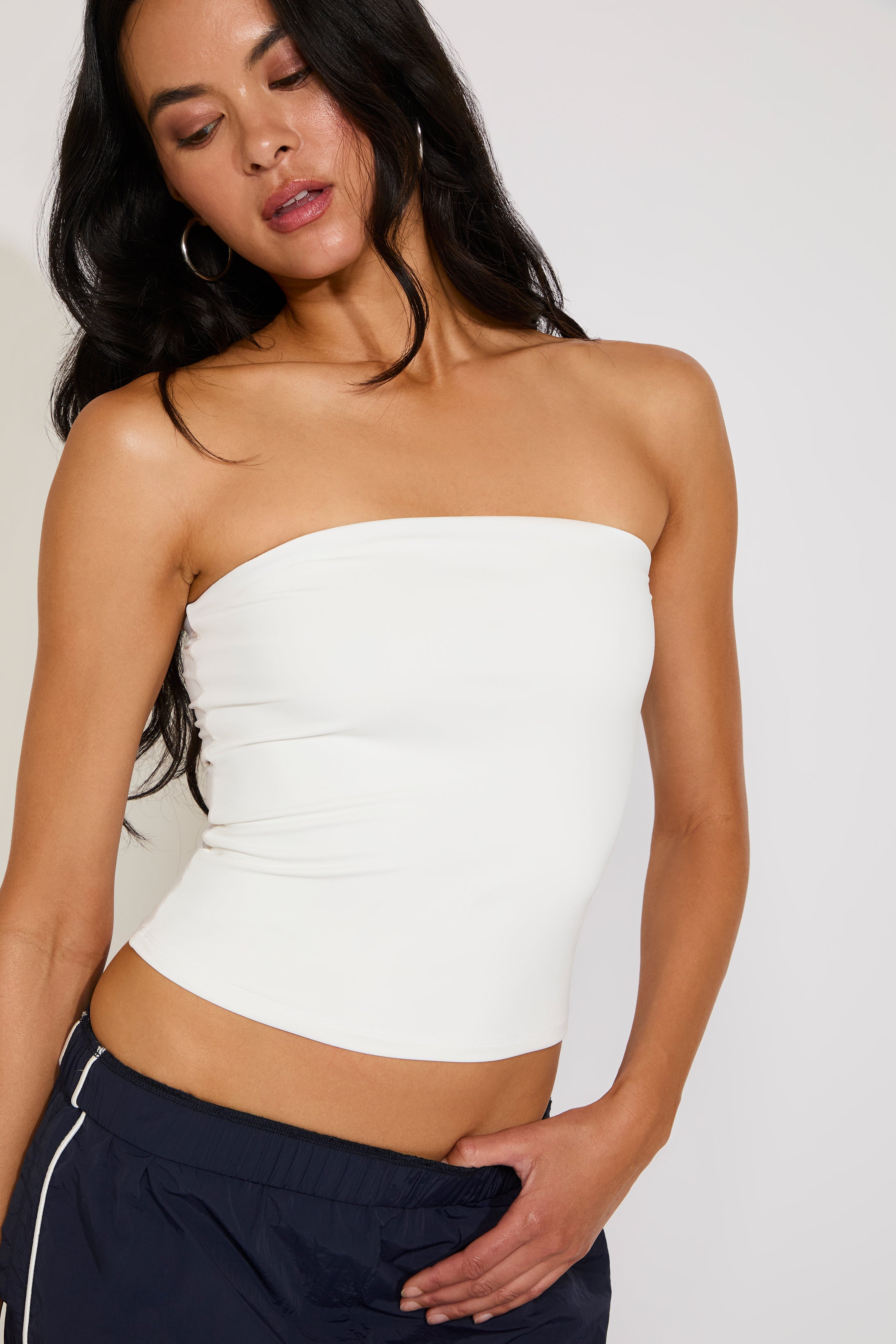 Woman wearing a white strapless top against a plain background