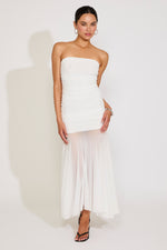 Woman wearing a strapless white dress with a sheer overlay on a white background