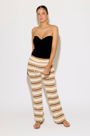 Woman wearing a black strapless top and striped pants on a white background