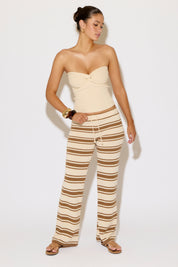 Woman wearing a strapless top and striped pants on a white background