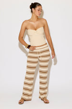 Woman wearing a strapless top and striped pants on a white background