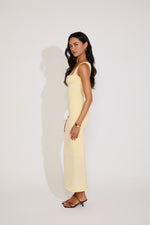 Woman wearing a light yellow dress against a white background