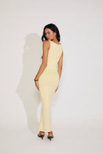 Woman wearing a light yellow sleeveless dress against a white background