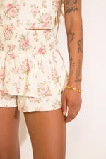 A model wearing a floral print halter top and tiered mini skirt set