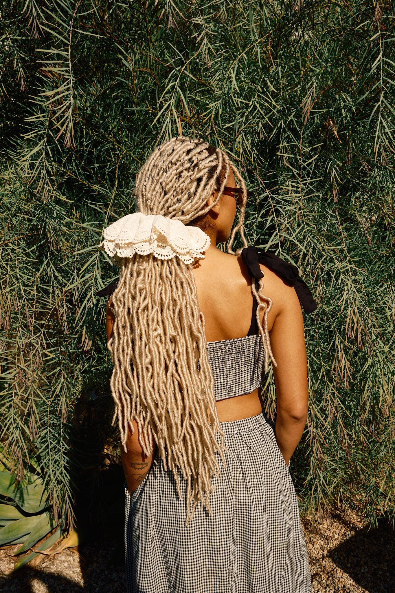 A person wearing a high rise black and white checkered maxi skirt with a crop top and white sneakers standing outdoors.