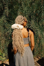 A person wearing a high rise black and white checkered maxi skirt with a crop top and white sneakers standing outdoors.