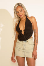 A person wearing a black top and beige acid wash denim A-line mini skort.